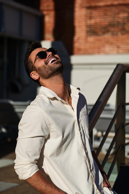 Joyful trendy ethnic man smiling on city street