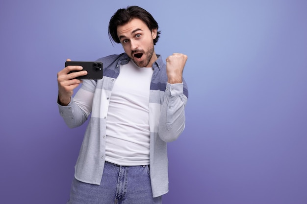 Joyful winner young brunette man with smartphone