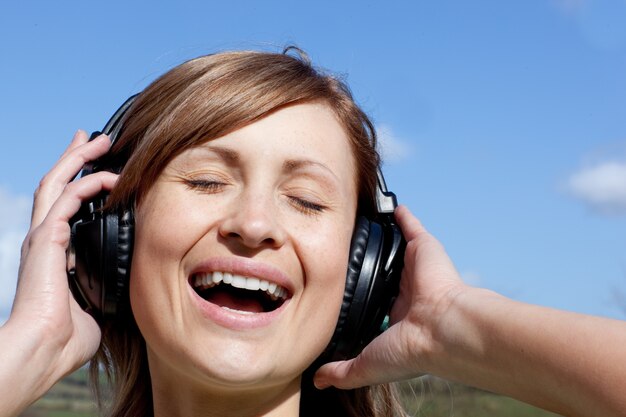 Photo joyful woman is listening music outdoor