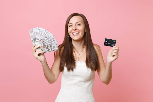 Joyful woman in lace white dress holding bundle lots of dollars, cash money and credit card