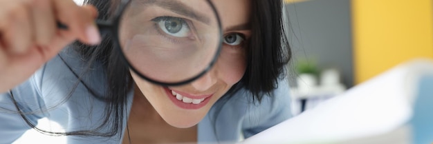 Joyful woman looking through a magnifying glass