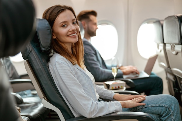 Joyful woman sitting in passenger chair in airplane