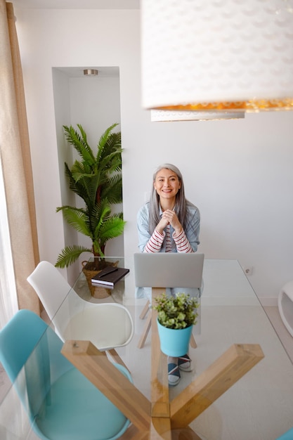 Joyful woman sitting at the table with notebook at home