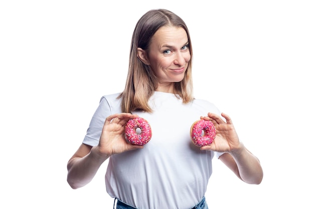 Joyful woman in a white tshirt with donuts with icing in her hands Health and delicious junk food Isolated on white background Space for text