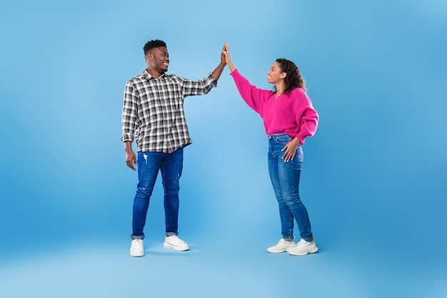 Joyful young african american couple giving high five to each other celebrating common success over