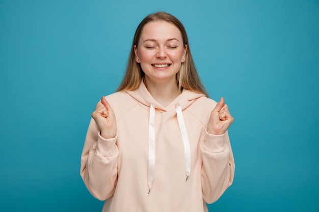 Joyful young blonde woman doing yes gesture with closed eyes 