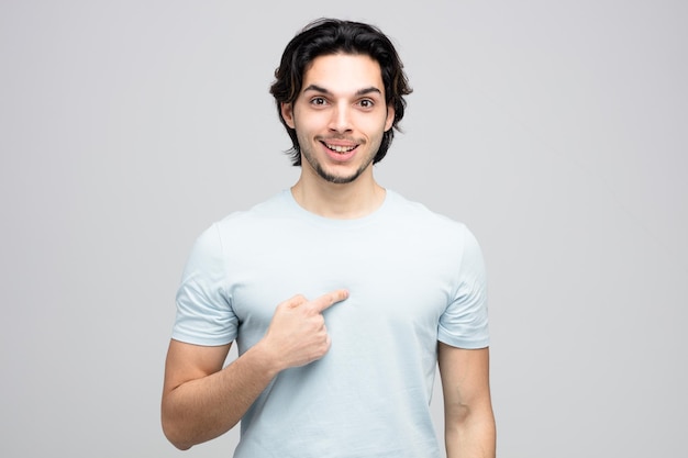 joyful young handsome man looking at camera pointing at himself isolated on white background