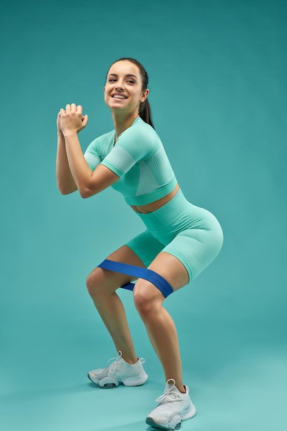 Joyful young woman doing exercise with resistance band