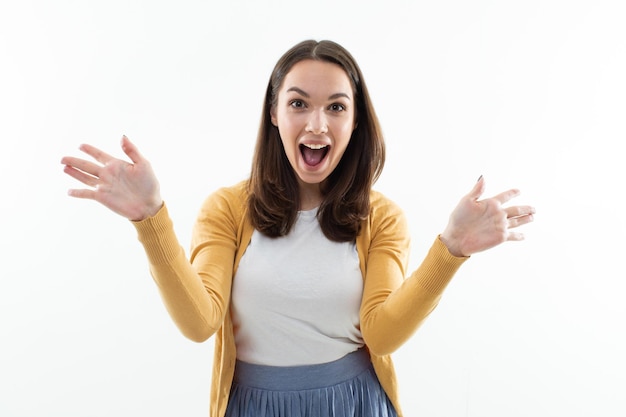 A joyful young woman looks into the camera Studio portrait of an emotional brunette on a white background isolated