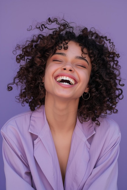 Joyful young woman with curly hair captured in a playful and carefree moment with a radiant smile against a bright backdrop