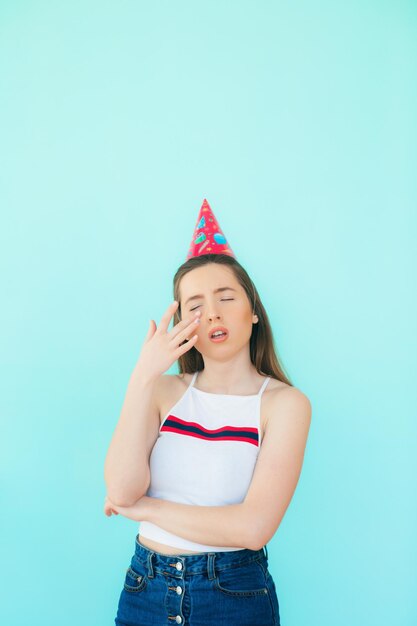 Joyous attractive young long haired woman in cap being excited and surprised posing