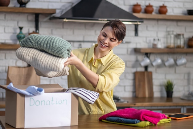 Joyous Caucasian girl preparing clothes for donation