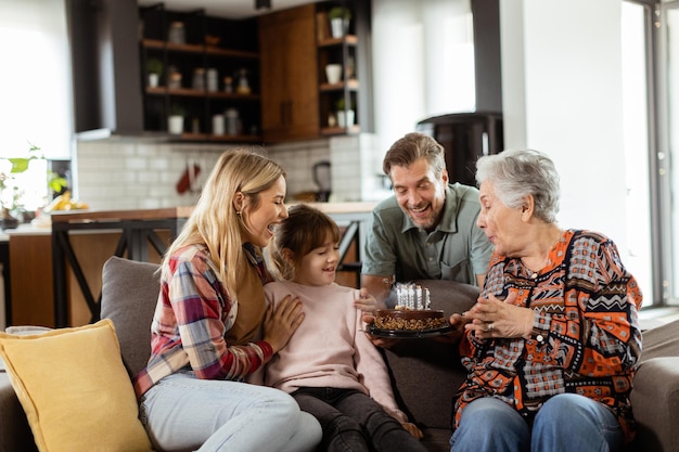 Joyous Family Celebrating Grandmothers Birthday With Cake in a Cozy Living Room