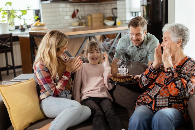 Joyous Family Celebrating Grandmothers Birthday With Cake in a Cozy Living Room