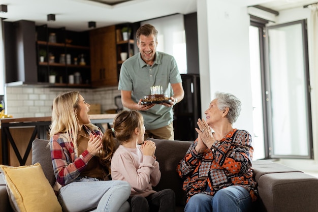 Joyous Family Celebrating Grandmothers Birthday With Cake in a Cozy Living Room