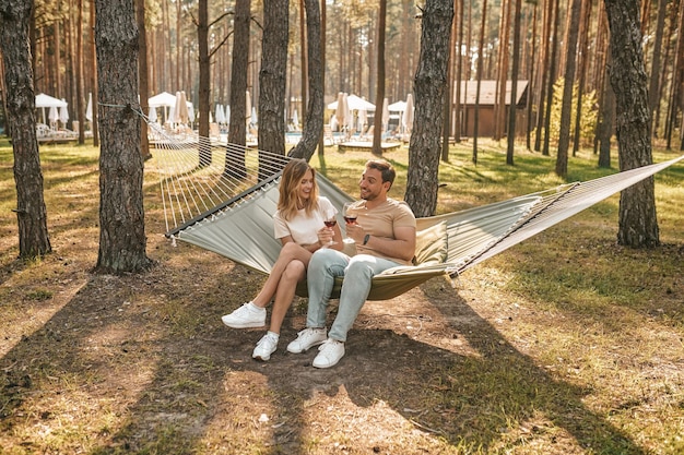 Joyous lady clinking glasses with her pleased romantic partner