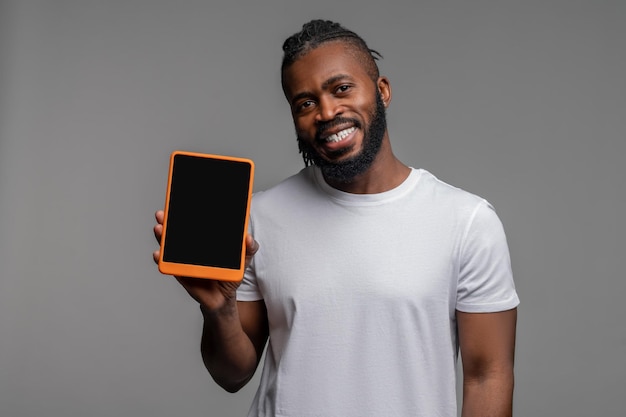 Joyous young man showing off his gadget