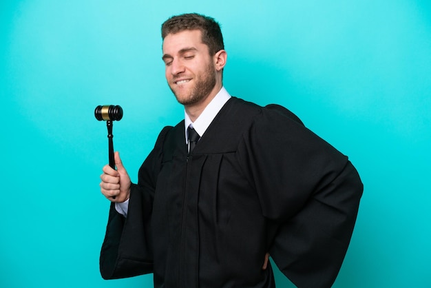 Judge caucasian man isolated on blue background suffering from backache for having made an effort