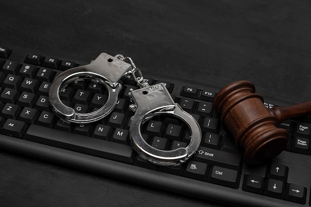 Judge gavel and handcuffs on computer keyboard. Cyber crime . Legal liability on the Internet. Online piracy.