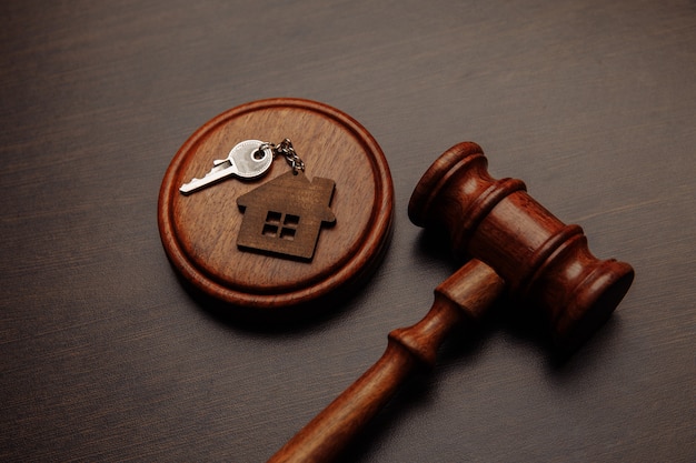 Judge gavel and key chain in shape of two splited part of house on wooden