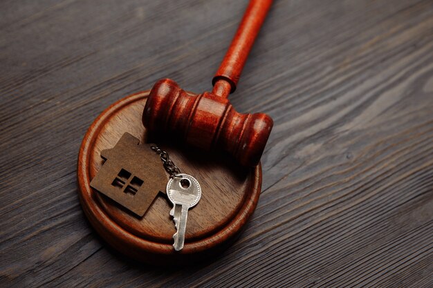 Judge gavel and key chain in shape of two splited part of house on wooden