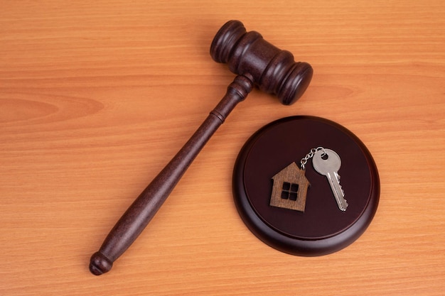 Judge gavel and key chain in shape of two splitted part of house on wooden background Concept of real estate auction or dividing house when divorce division of property real estate law system