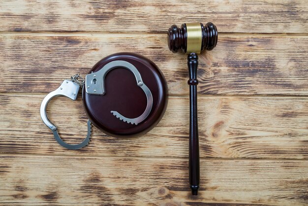 Judge gavel with handcuffs on wooden background