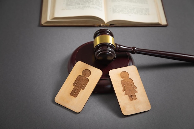 Judge gavel with a male and female wooden symbols on the black background