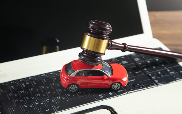 Judge gavel with a red toy car on the computer keyboard Online car auction concept