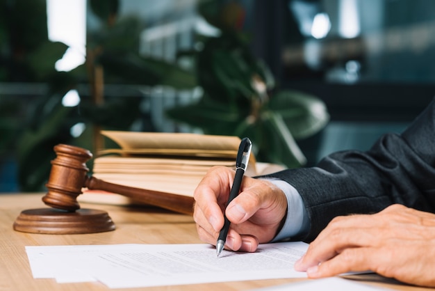 Judge holding pen checking document over wooden desk