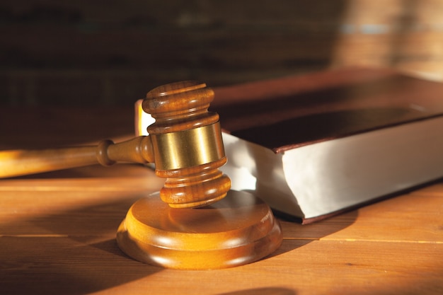 Judge's hammer on a book on a wooden table