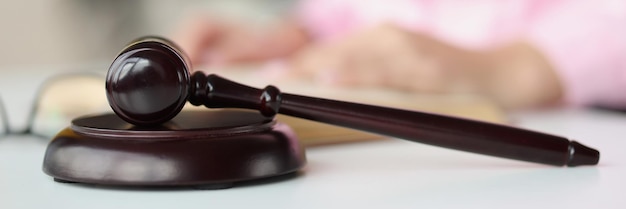 Judge wooden gavel lying on table against background of woman with book closeup judicial and