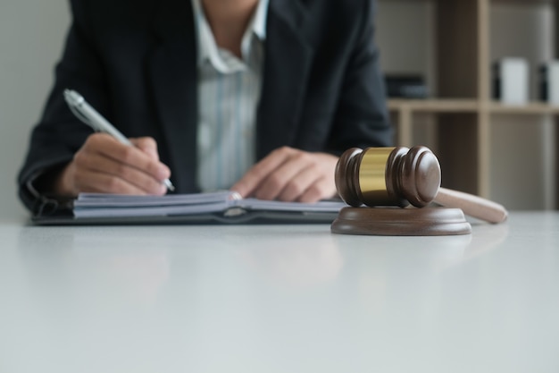 Judge writing note with legal law gavel on desk.