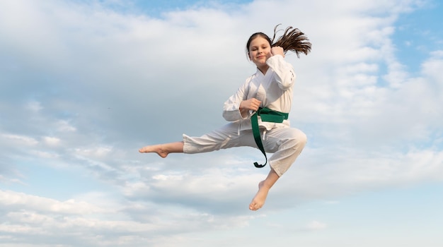 Judo concept teen girl practicing judo girl judo fighter jumping on sky background