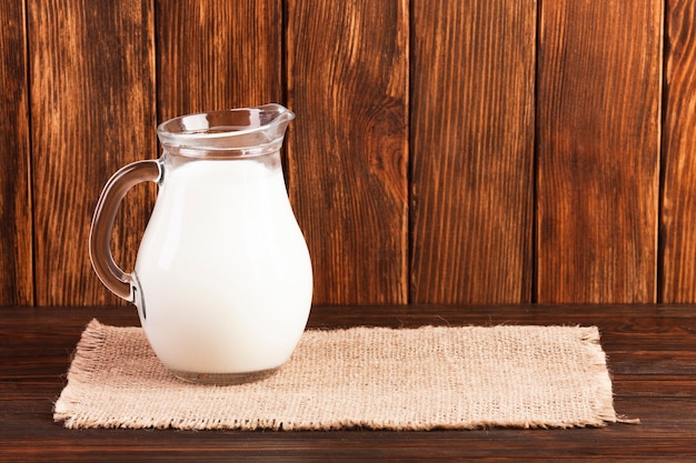 Jug of fresh milk on wooden table