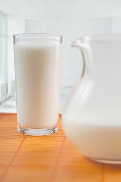 The jug and glass with milk stand on a table