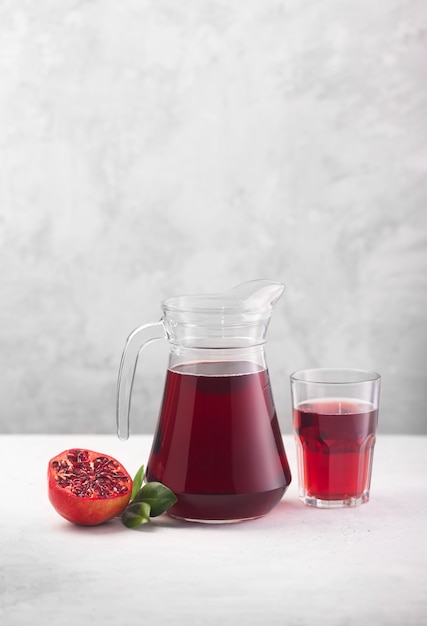 A Jug of pomegranate juice with fresh pomegranate fruits on gray background. It contains vitamins and minerals, helps in increasing hemoglobin