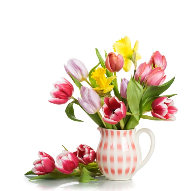 Jug with spring flowers on white background