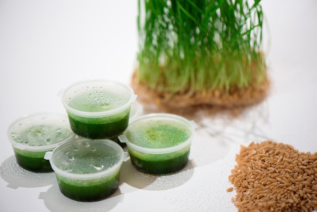 Juice and fresh wheat grass on the white table