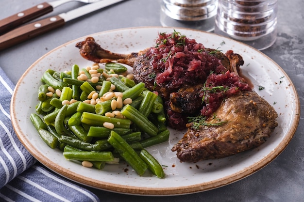 Juicy baked duck legs with green haricot and pine nuts