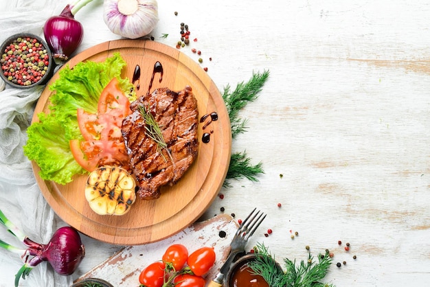 Juicy baked pork steak with vegetables on the board Top view