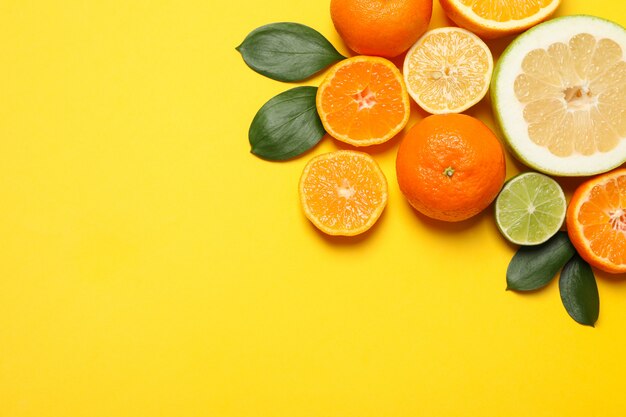 Juicy citrus fruits on yellow background, space for text