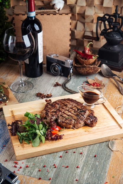 Juicy cooked ribeye steak with sauce and salad