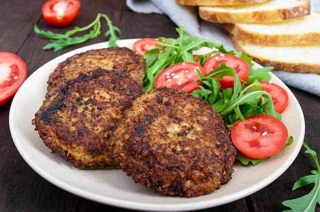 Juicy cutlets on a plate with a salad of tomatoes and arugula on a dark wooden.