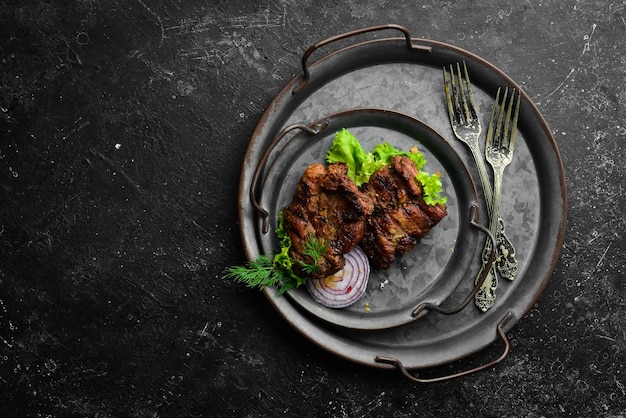 Juicy fried pork steak with spices on a black stone plate Top view Free copy space