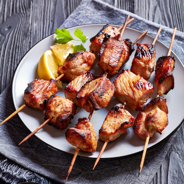 Juicy grilled pork kebabs on a plate with lemon wedges and ketchup horizontal view from above