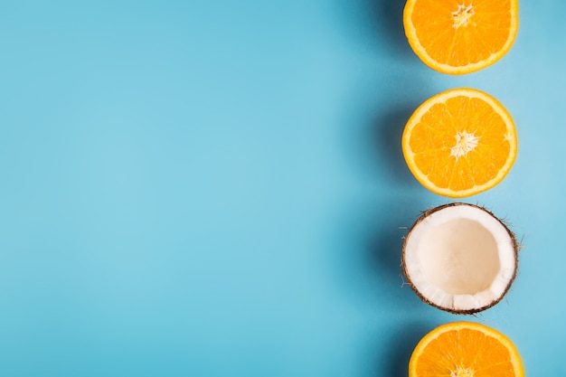 Juicy orange halves and white coconut halves on a bright, blue summer background