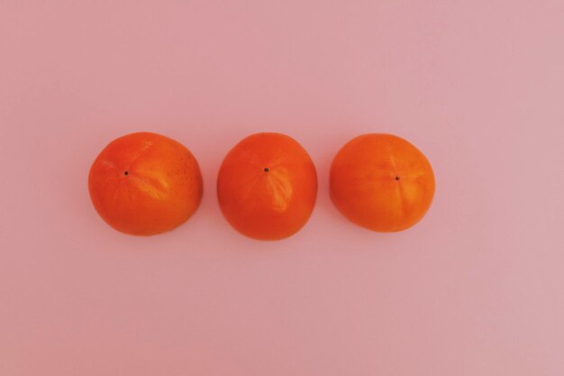 Juicy orange persimmon on a pink background