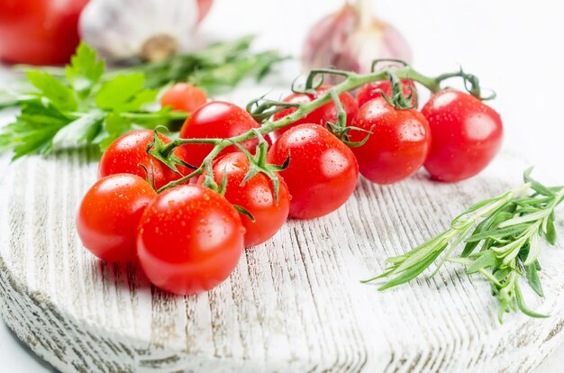 juicy organic red cherry tomatoes, rosemary,  garlic and spices on table