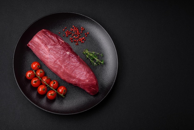 Juicy raw beef with spices salt and herbs on a dark concrete background